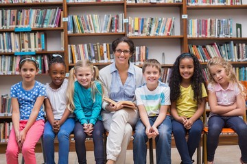 Cute pupils and teacher reading in library