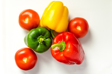 Paprika rot gelb gruen und Tomate nebeneinander auf weiss
