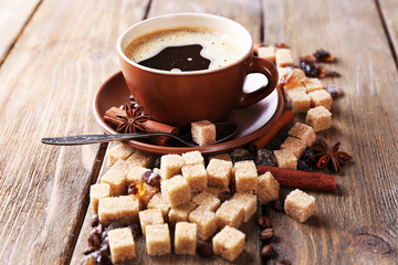 Brown sugar, spices and cup of coffee on wooden background