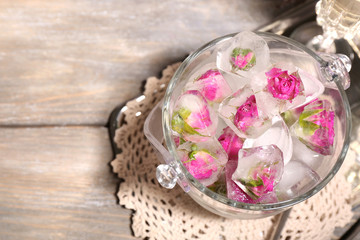 Ice cubes with rose flowers in glass bucket and two glasses