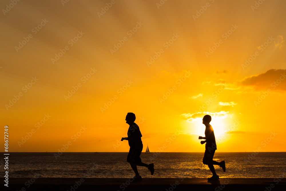 Wall mural silhouette of people jogging at the beach with sunset backgroun