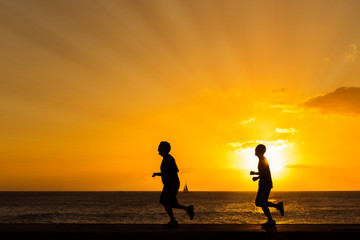 Silhouette of people  jogging at the beach with sunset backgroun