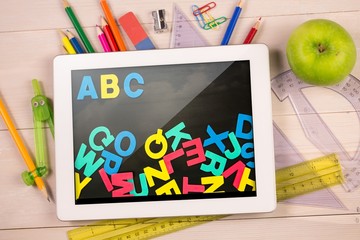Composite image of digital tablet on students desk