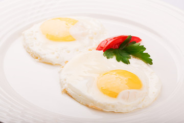 Fried eggs decorated with parsley and tomato