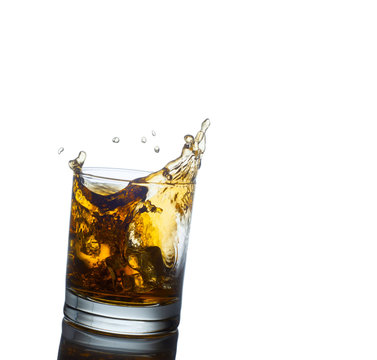 Scotch whiskey splashing out of glass. Isolated on white  backgr