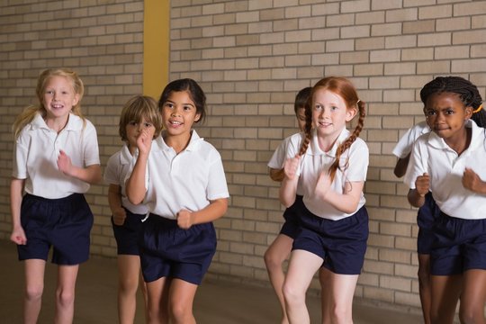 Cute pupils warming up in PE uniform
