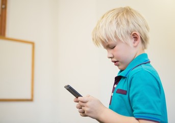 Fototapeta premium Cute pupil using smartphone in classroom