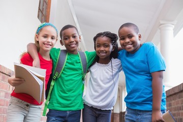 Cute pupils smiling at camera in hallway