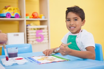 Fototapeta premium Cute little boy painting at table in classroom