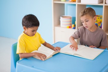 Naklejka premium Cute little boys reading at desk in classroom