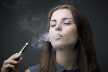 Elegant woman smoking e-cigarette with smoke