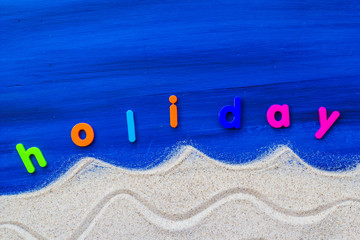 Obraz premium word holiday laid sand blue board