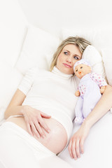 pregnant woman resting in bed with a doll