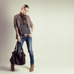 Glamour pretty girl holding stylish leather bag in studio