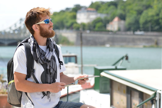 Lost bearded male tourist holding a map and gesturing with hands