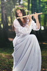 Beautiful woman playing a flute in the woods © captblack76