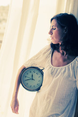 beautiful young woman holding a big clock