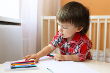 lovely baby boy painting with wax pencils