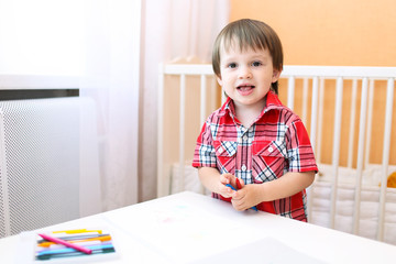 little boy painting with wax pencils