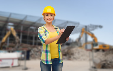 Obraz premium smiling woman in helmet with clipboard