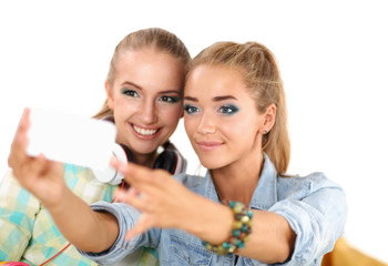 Two girls taking pictures on the phone at home