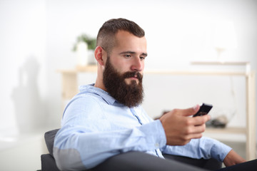 Businessman sitting the sofa in office lobby with phone,