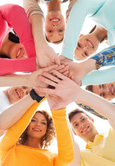 smiling teenagers with hands on top of each other