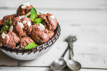 Chocolate ice cream with mint and almonds on wooden background