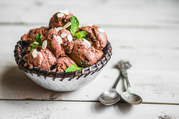 Chocolate ice cream with mint and almonds on wooden background