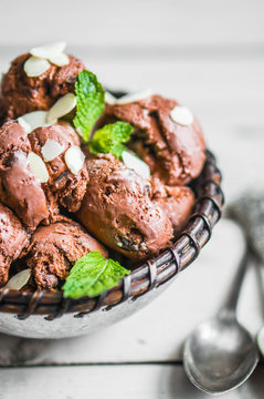 Chocolate ice cream with mint and almonds on wooden background