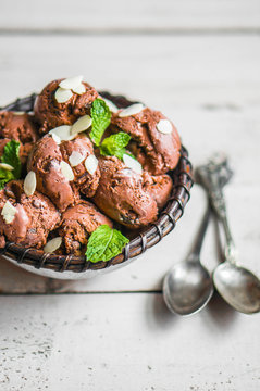 Chocolate ice cream with mint and almonds on wooden background