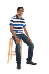 Fototapeta premium Full body indian man sitting on a chair over white background