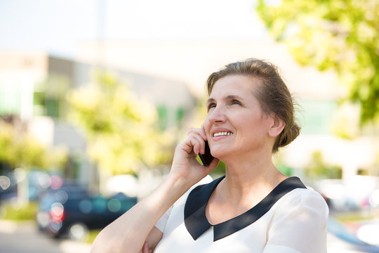 Happy Woman Talking on a Phone outside street background 