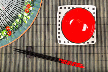 Two chopsticks on sushi mat background with plate