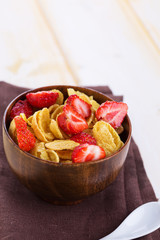 Cornflakes with strawberries  in bowl on table