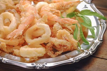 Fried calamari and shrimps on wooden table