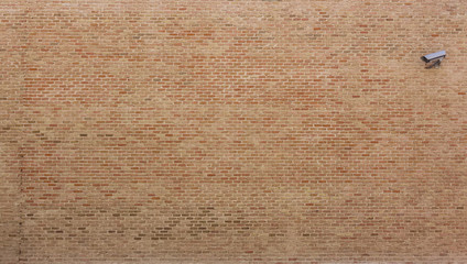 Background of red bricks wall with a surveillance camera in one