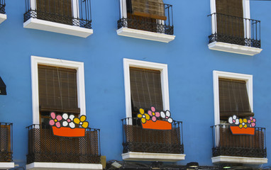 Fototapeta na wymiar nice balconies with colorful flowers in a blue and white house