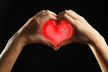 Human hands making heart on black background