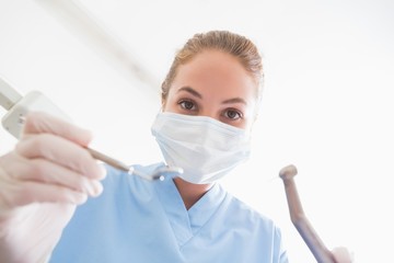 Naklejka premium Dentist in surgical mask holding tools over patient