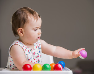 Fototapeta na wymiar cute baby girl playing with colorful balls
