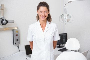 Dental assistant smiling at camera beside chair