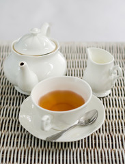 Fototapeta na wymiar Cup of tea with little milk jar and teapot