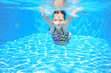 Happy active underwater child swims in pool and having fun