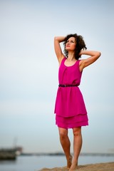 Young woman in a red dress and curly hair on the water coast