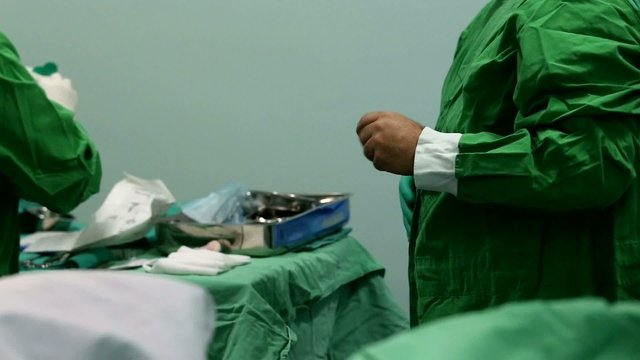 Assistant putting gloves to the surgeon to avoid contamination