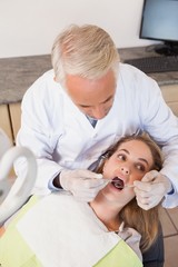 Obraz premium Dentist examining a patients teeth in the dentists chair