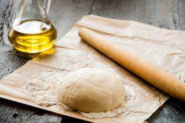 wooden rolling pin with freshly prepared dough for pizza