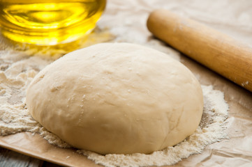 Fototapeta na wymiar wooden rolling pin with freshly prepared dough for pizza