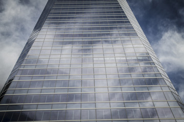 futuristic, skyscraper with glass facade and clouds reflected in